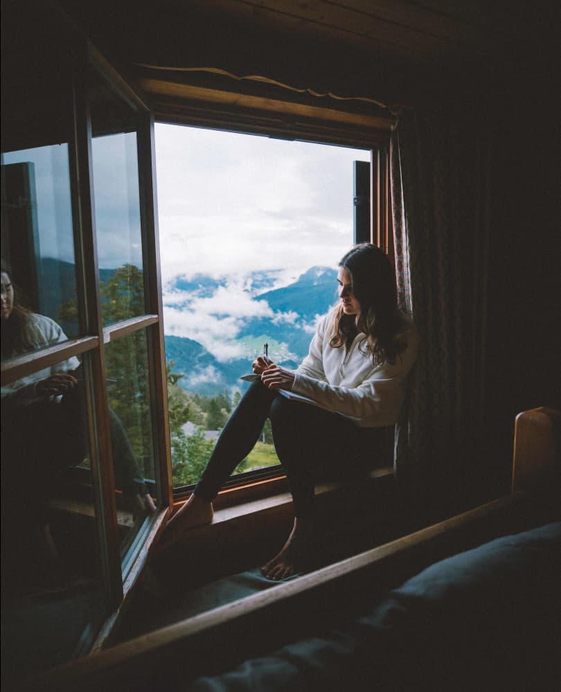 Photo of Giulia in her home in the Dolomites, sitting at the edge of a window