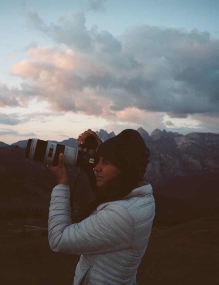 Film photo of Giulia taking a photo with a zoom lens in the moutains