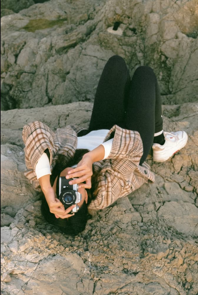 Photo of Giulia, laying on the ground and taking a photo of the photograph with a film camera